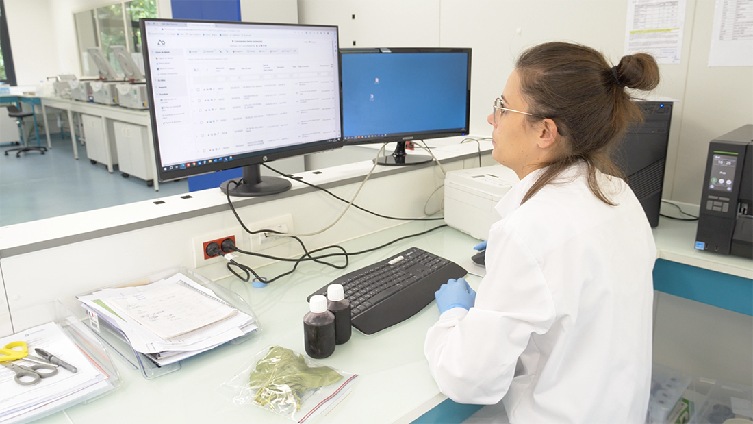 Technicienne de laboratoire analysant des résultats sur un poste à deux écrans