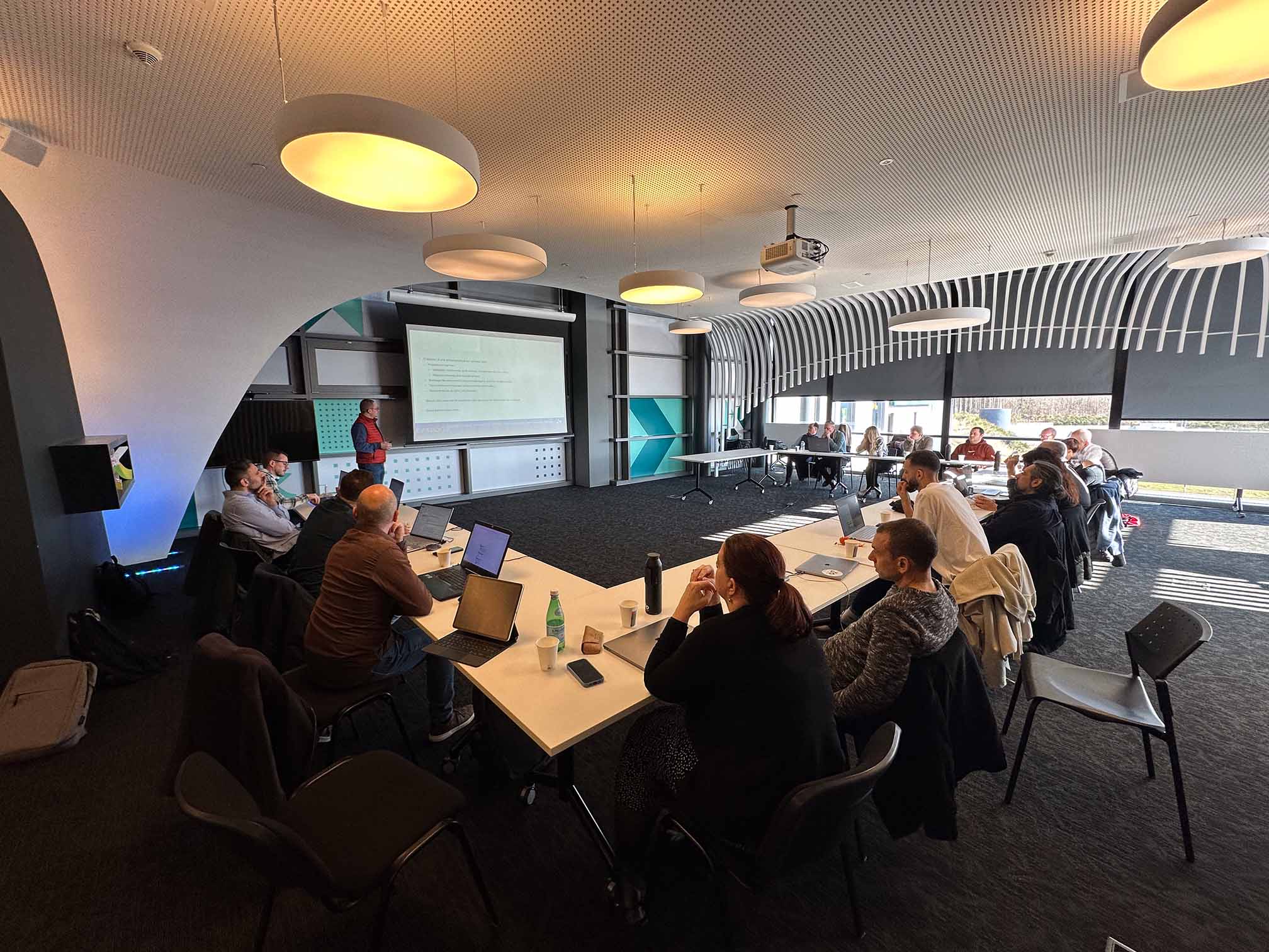 Participants réunis en salle pour une présentation projetée sur grand écran